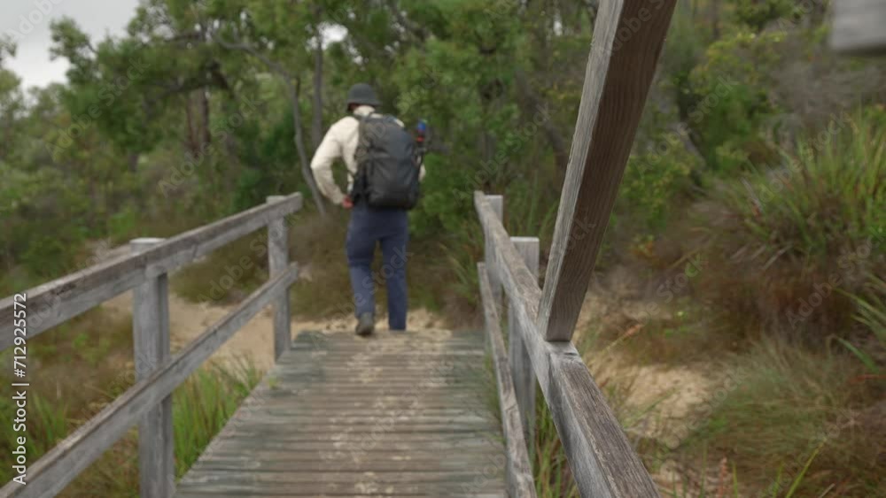 Man walking down wooden steps along a coastal beach trail, walking through the frame and out of shot. Man walking down wooden steps along a coastal beach trail, walking through the frame and out of shot.