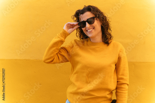Positive woman in sunglasses near wall