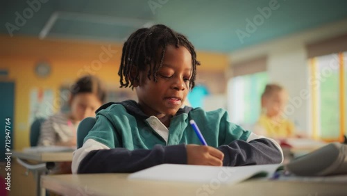 Talented Small African American Boy Asking Teacher a Question in Class. Portrait of a Happy Elementary School Student Studying Hard, Learning New Things, Getting Modern Education with Other Kids photo