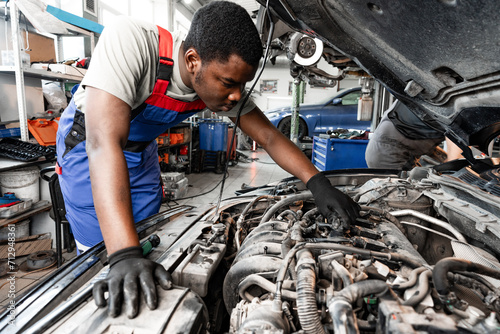 Young African auto mechanic checking car engine under the hood in auto service © fotofabrika
