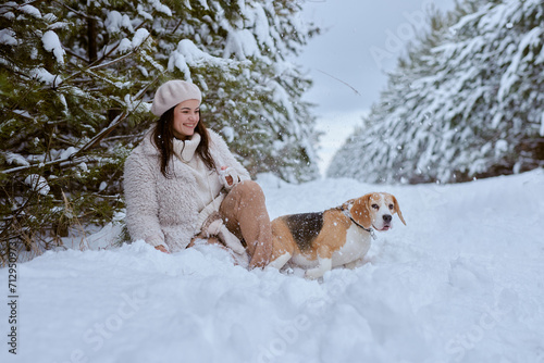 girl in winter clothes plays with Beagle dog in winter in the snow, winter holiday concept