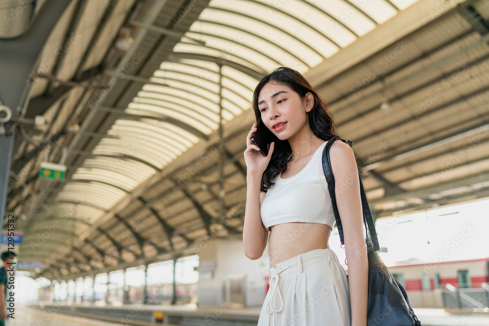 Asian woman using phone for social media while commuting at a train commuter station