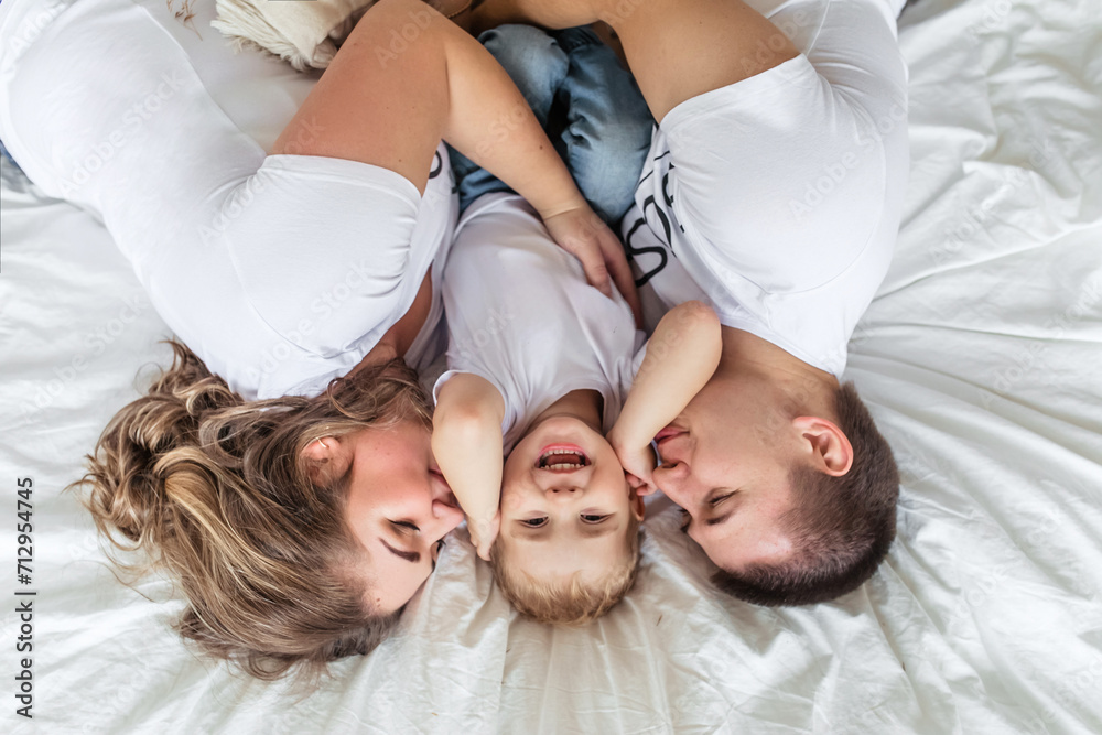 Family with baby in bed, kissing and hugging kid