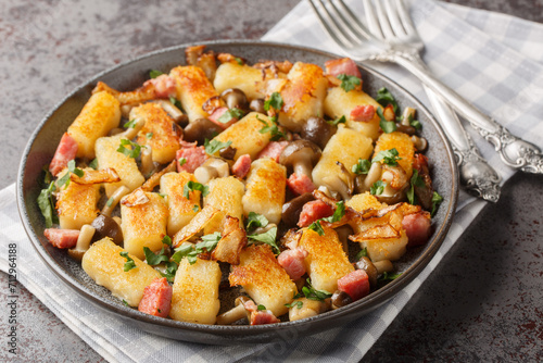 Potato dumpling originating from Poland kopytka served with bacon, onions and mushrooms close-up in a plate on the table. Horizontal