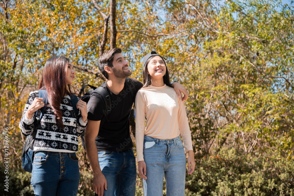 Happy Multi-ethnicity group of young friends enjoy hiking, walking, exploring in forest on vacation, female and man having fun in forest on beautiful autumn day, nature outdoor wild grass forest trip.