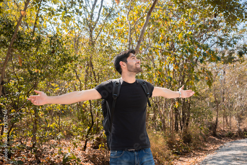 Caucasian man enjoying nature amidst mountains and trees during the weekend. Happy man spends his free time hiking, walking, exploring, adventure in forest beautiful autumn day.