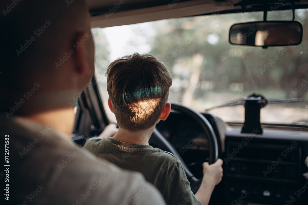 Dad teaches his son to drive a car view from the back Dad teaches his son to drive a car view from the back