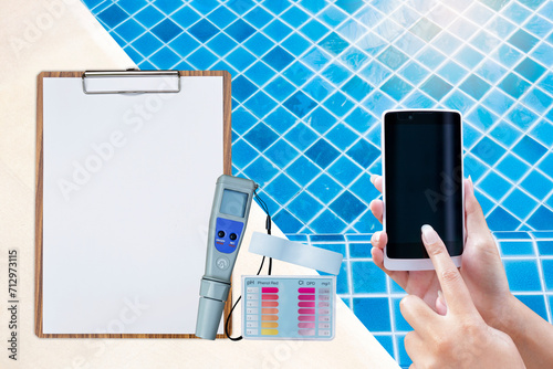 Online report and control for swimming pool water testing, pool maintenance and service, quality water tester, smartphone in girl hand with digital tester on clipboard  on swimming pool edge photo