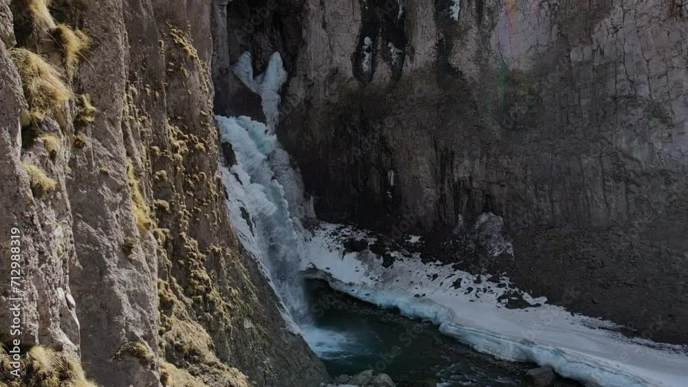 Winter drone view of Karakaya-Su waterfall. A powerful stream bursts out of the rocks. Icicles around the waterfall Winter drone view of Karakaya-Su waterfall. A powerful stream bursts out of the rocks. Icicles around the waterfall