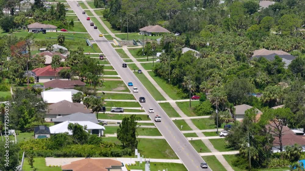 View from above of suburban street traffic with driving cars in American small town. Florida suburbs landscape with private homes in quiet residential area View from above of suburban street traffic with driving cars in American small town. Florida suburbs landscape with private homes in quiet residential area