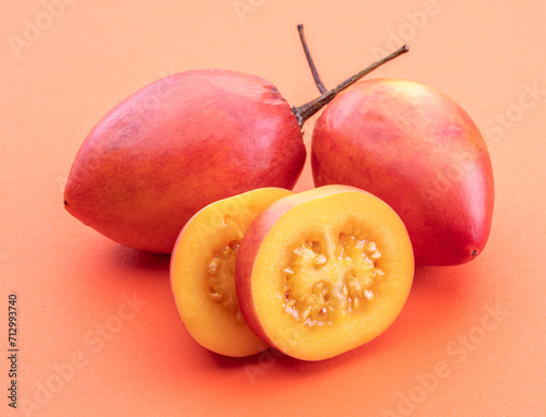 Ripe tamarillo fruits with slices leaves isolated on a orange background.