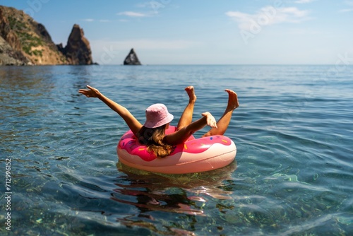 Summer vacation woman in hat floats on an inflatable donut mattress. Happy woman relaxing and enjoying family summer travel holidays travel on the sea. photo