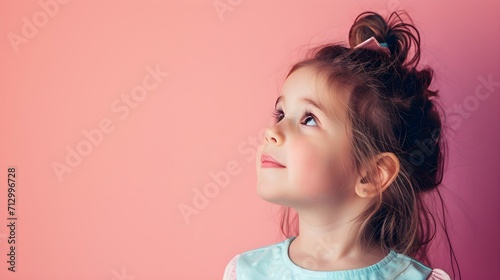 Close up potrait of cute little girl looking above. Concept of curious ,imiginative, new idea, solution from young and smart kids. Pastel color background with copy space. photo