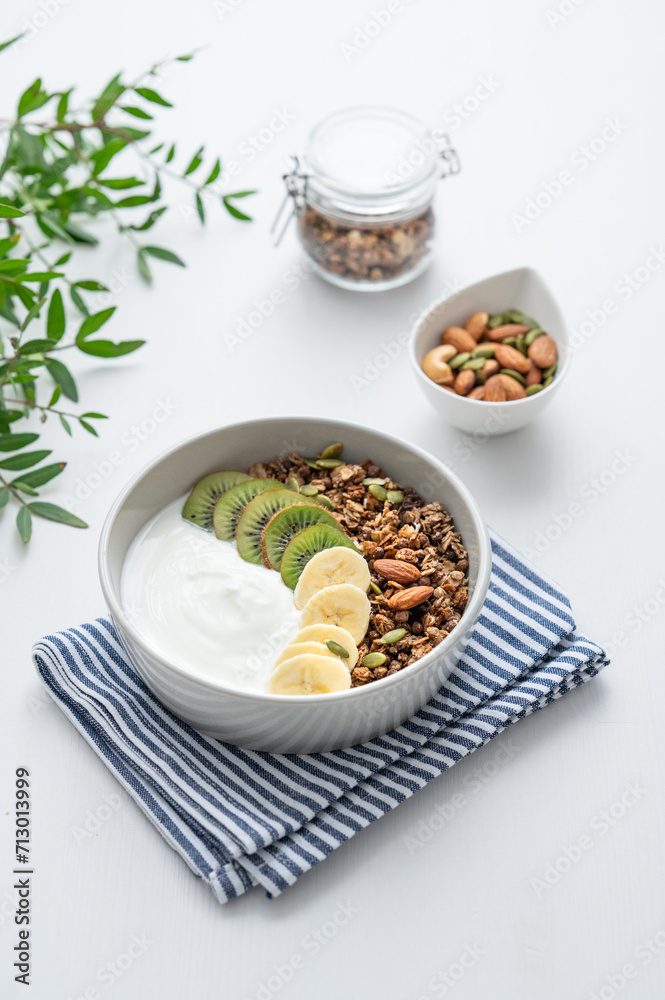 Granola with banana and kiwi on a white table with a green branch. Granola with banana and kiwi on a white table with a green branch.