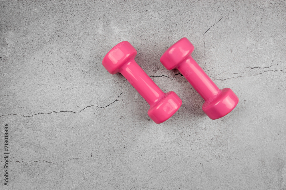 Top view of pink dumbbells on grey concrete background. Fitness, sport, health flat lay. Copy space. Top view of pink dumbbells on grey concrete background. Fitness, sport, health flat lay. Copy space.