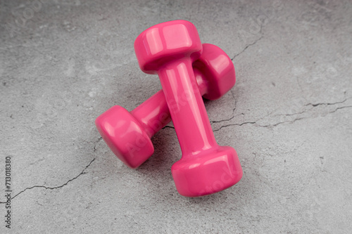 Pink dumbbells on grey concrete background. Fitness, sport, health.