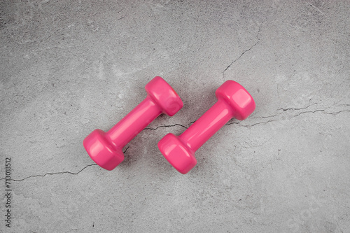 Top view of pink dumbbells on grey concrete background. Fitness, sport, health flat lay. Copy space.