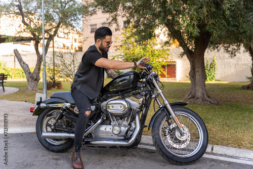 Hipster guitarist with his motorcycle. Rock aesthetic.