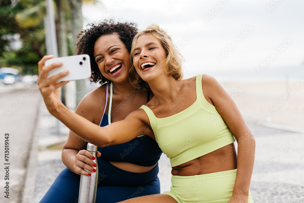 Fitness friends taking workout selfies on the promenade together - obrazy, fototapety, plakaty 