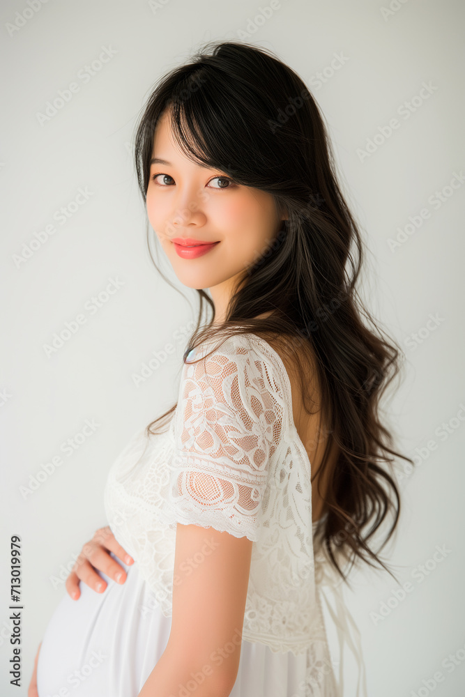 Portrait of beautiful asian young pregnant woman touching belly standing on colour background Portrait of beautiful asian young pregnant woman touching belly standing on colour background