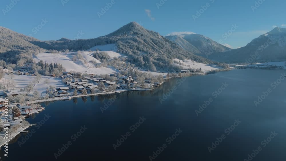 Lake Schliersee with white snow winter landscape, mountains and dark blue water. Traditional old village with a church in Bavaria, Germany. Lake Schliersee with white snow winter landscape, mountains and dark blue water. Traditional old village with a church in Bavaria, Germany.