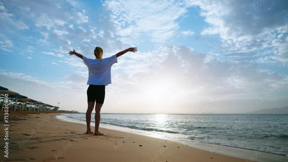 Barefooted woman doing yoga standing balancing in tree pose on sandy sea ocean beach at morning. Female stretching relaxing meditate concentrating on asana. Body care wellness sport activity concept. Barefooted woman doing yoga standing balancing in tree pose on sandy sea ocean beach at morning. Female stretching relaxing meditate concentrating on asana. Body care wellness sport activity concept.