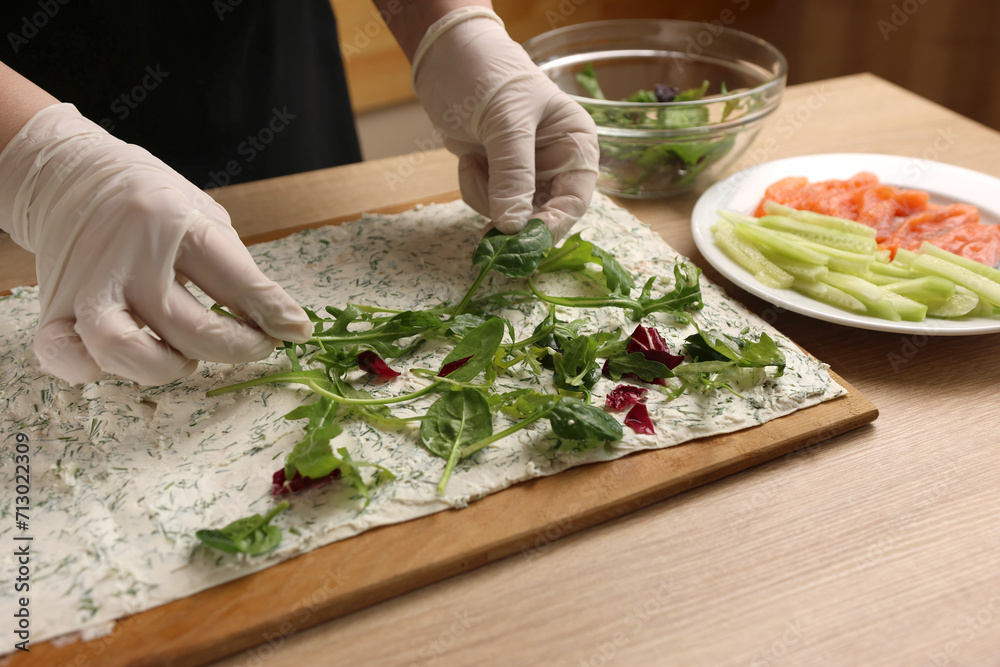 Greens are added to pita bread with cheese. Preparation of a roll with cheese, fish and vegetables Greens are added to pita bread with cheese. Preparation of a roll with cheese, fish and vegetables