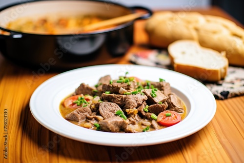 side view of beef stroganoff in a shallow dish, bread slices on the side
