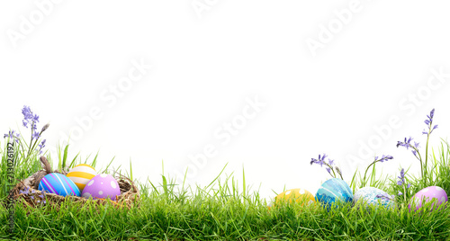 A blank template of three painted easter eggs in a birds nest and a line of eggs on the right celebrating a Happy Easter on green grass and isolated on transparent background.	
