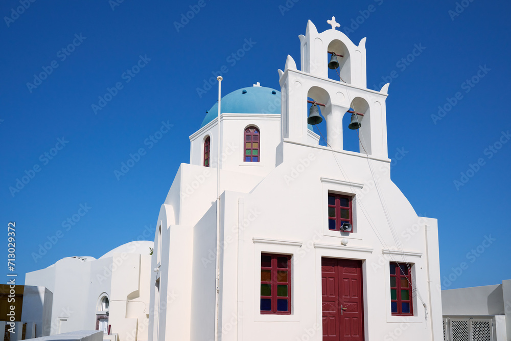 Oia town on Santorini island, Greece. Traditional white church with blue domes over the Caldera, Aegean sea