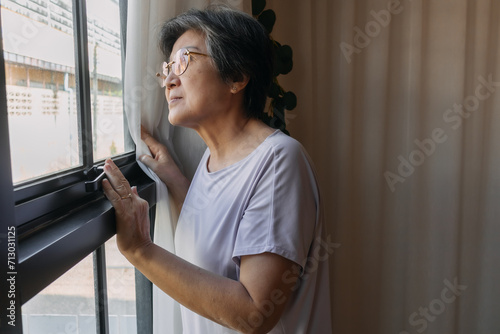 Obraz na plátně Asian Thai Chinese senior elderly woman looks sadly outside the window