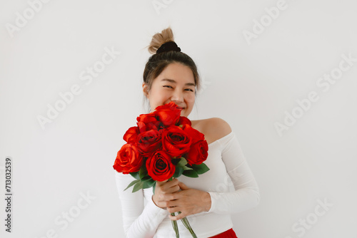 Asian woman holding red roses, Happy smiling receiving flowers on Valentines day and looking at camera, standing isolated over white background wall. photo