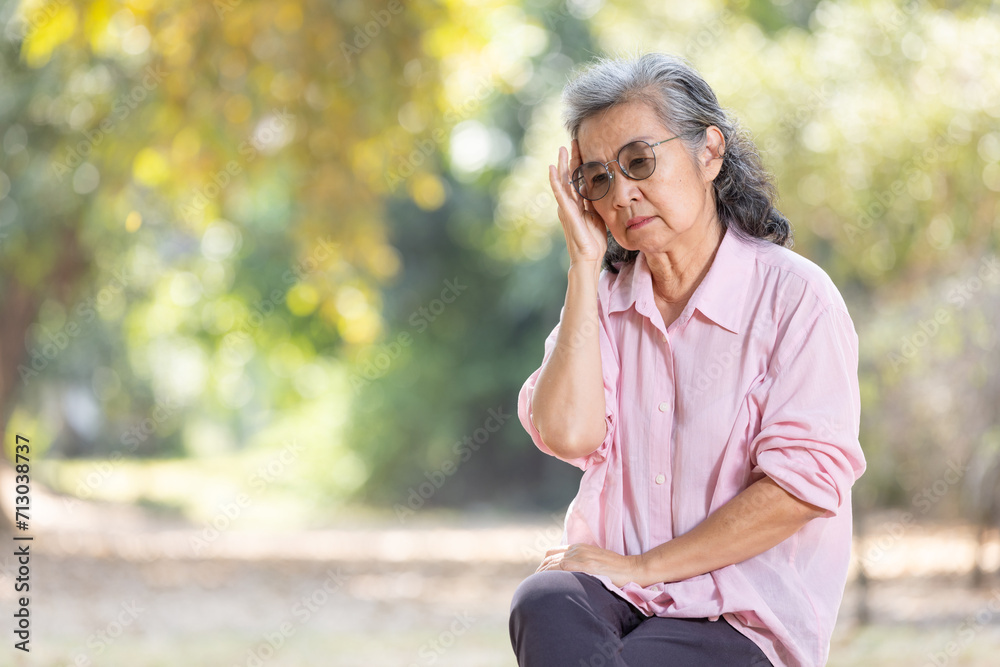 Asia senior woman sitting on bench at park and looking away.Mental health. Asia senior woman sitting on bench at park and looking away.Mental health.