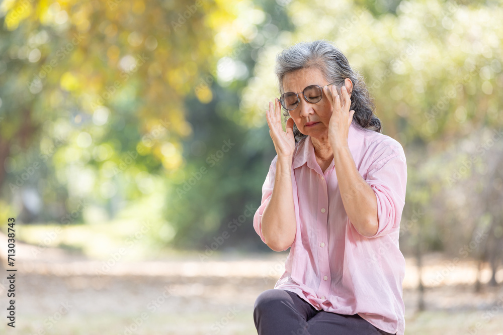 Asia senior woman sitting on bench at park and looking away.Mental health.