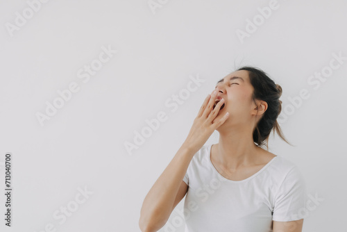 Happy asian Thai woman hand covering mouth while laughing, feeling glad wear white and bun hairstyle, standing isolated over white background wall.