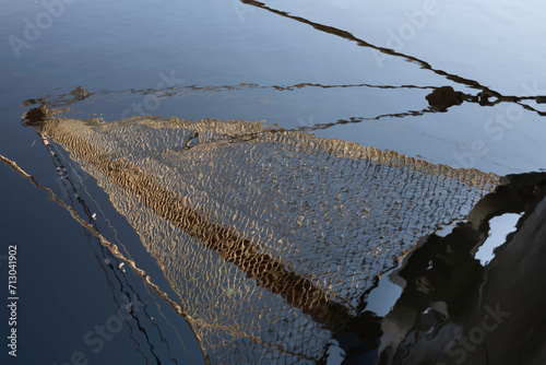 Foto Ship's bow with jib boom and tightly knotted jib net in front of the foremast of a sailing ship mirrored in the rippling water