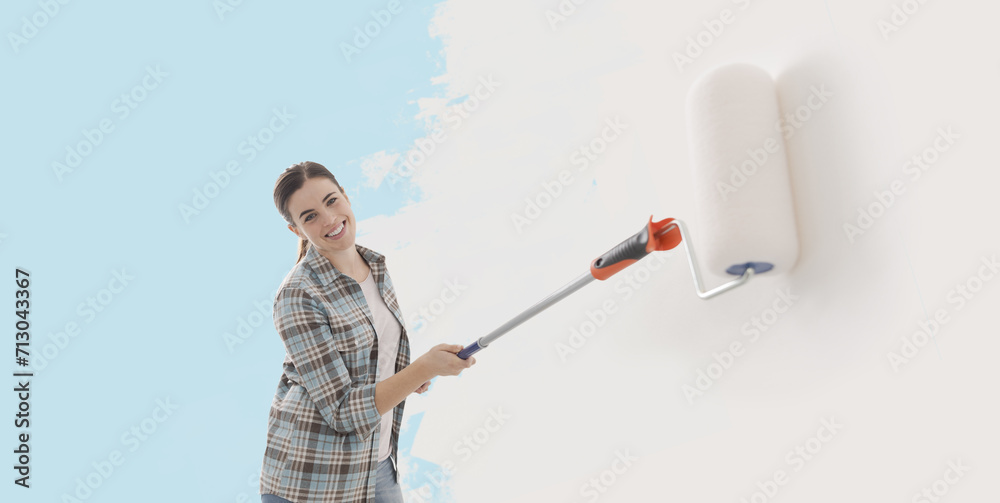 Happy woman painting walls with a roller Happy woman painting walls with a roller