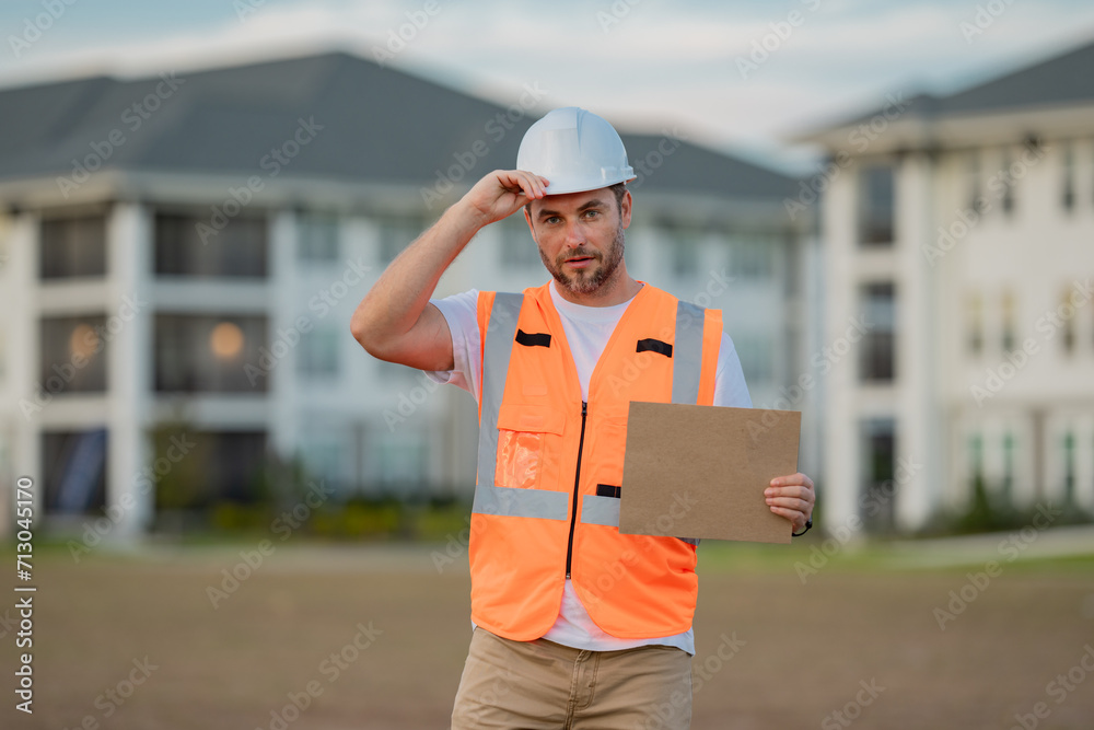 Engineer hold paper board for text. Builder showing signboard placard banner, poster. Portrait of builder in a construction site. Builder ready to build new house. Engineer hold paper board for text. Builder showing signboard placard banner, poster. Portrait of builder in a construction site. Builder ready to build new house.