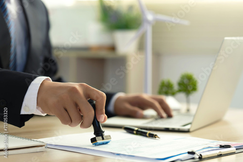Businessman Hand Stamping With Approved Stamp On Document At Desk. validates and manages business documents and agreements, and approves business cooperation to comply with environmental laws. ESG photo