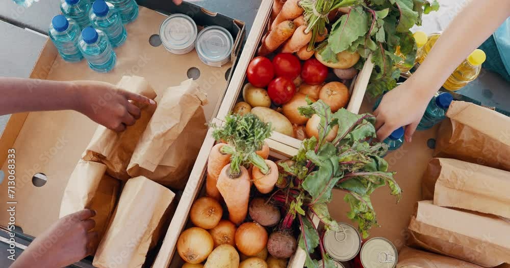 Hands, groceries and food drive with people packing box from above for charity or community service. Donation, mindfulness and poverty with volunteer team collecting essential supplies closeup