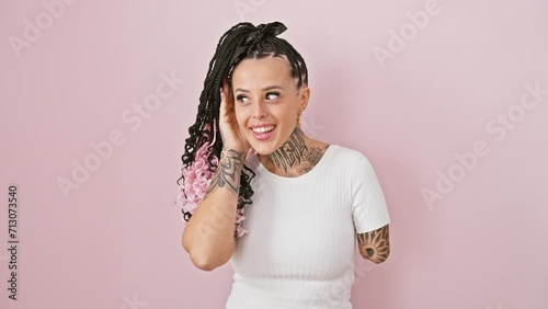 Hispanic amputee woman joyfully standing over pink isolated background, playfully listens to juicy gossip with hand over ear. deafness not deterring her spark! photo