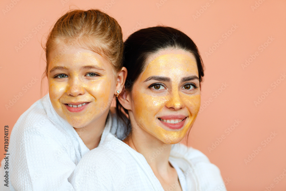 Family spa day. Young beautiful mother and little daughter in bathrobes doing beauty treatment together Family spa day. Young beautiful mother and little daughter in bathrobes doing beauty treatment together