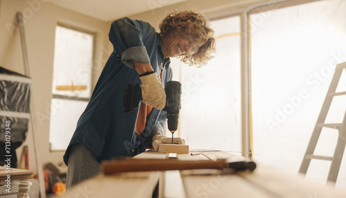 Fotografie Woman smiling while renovating her kitchen with hand tools