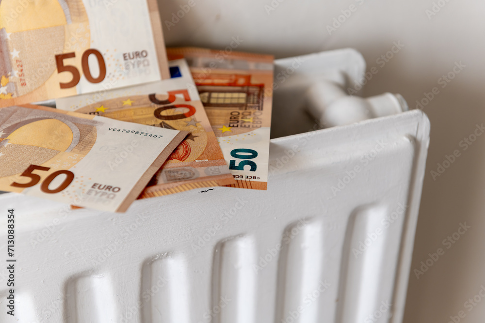 A pile of 50 Euro bank notes on top of a central heating radiator. A European heating utilities cost concept.