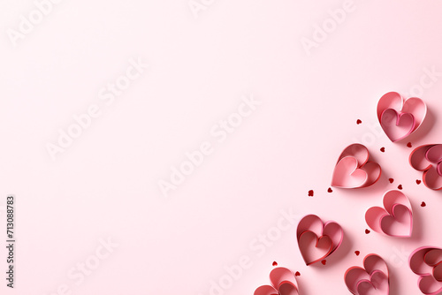 Valentine's Day greeting card design. Flat lay composition with paper cut hearts and confetti on pink background. Top view with copy space.