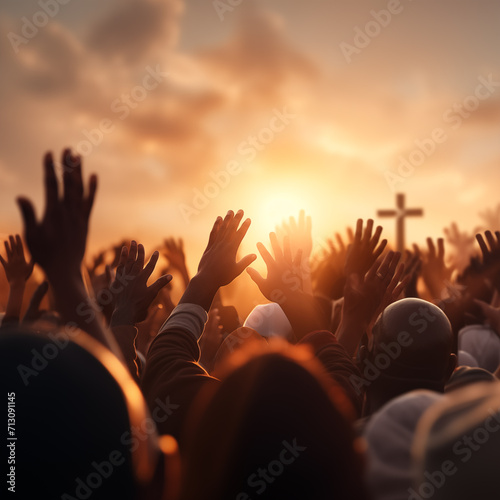 Worshipers rising hands in front of bright sunrise with cross, Easter background