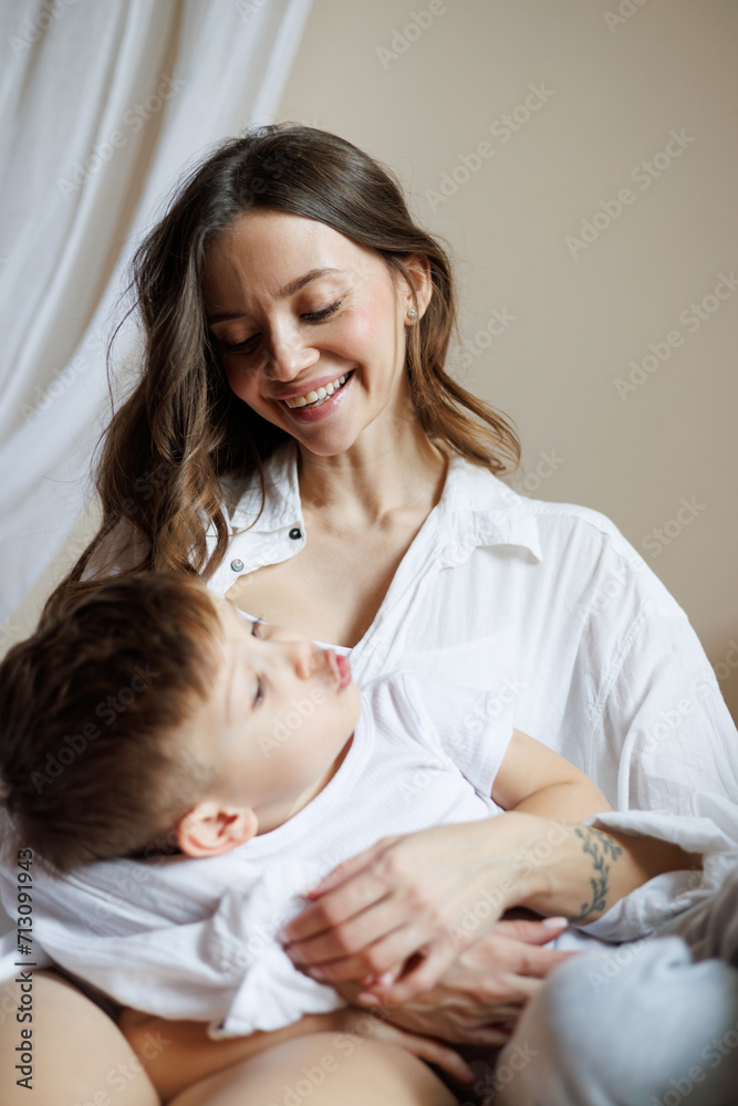 Smiling mother hugging toddler son in pajama on bed at home Smiling mother hugging toddler son in pajama on bed at home