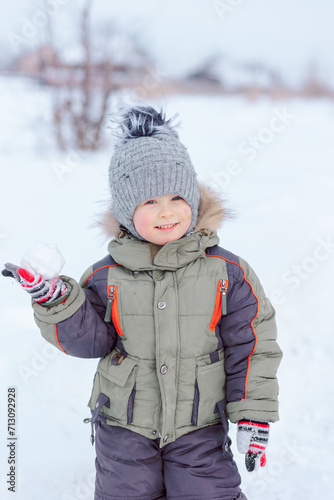 Baby enjoys winter playing snowballs