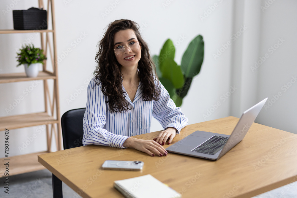Happy and smiling businesswoman typing on laptop at work inside office building Happy and smiling businesswoman typing on laptop at work inside office building