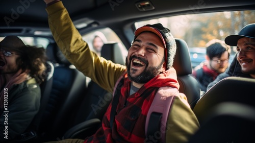 A man in red vest and hat, laughing and lifting his arm, sits in a car with happy friends. Everyone in the car is happy, the man in red is raising his arm. 